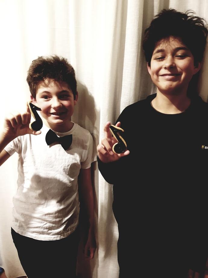 Happy piano students holding musical note cookies